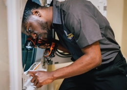 Technician examining an outdoor dryer vent cover.